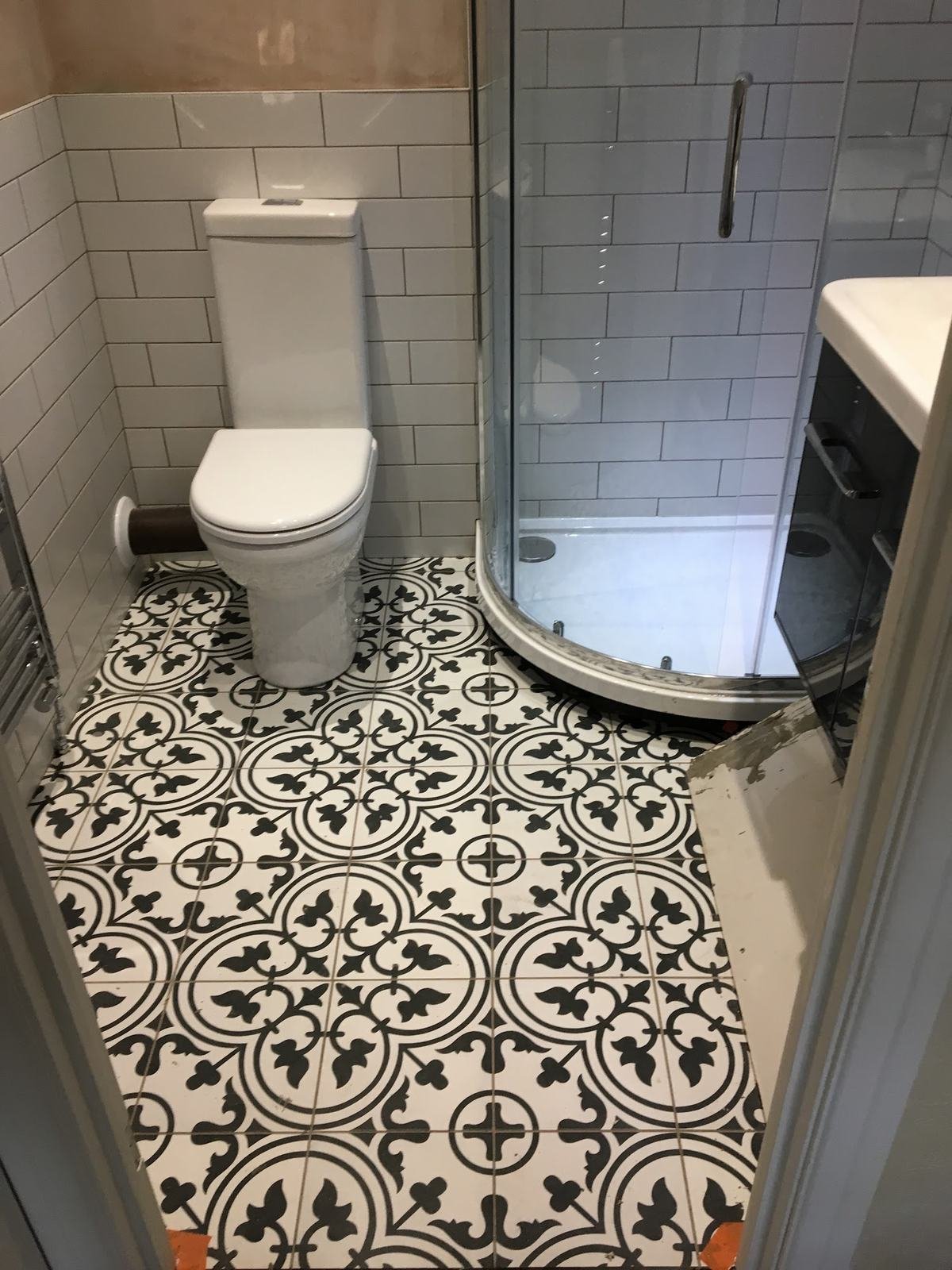 Shower room floor in black and white patterned tiles with white metro walls