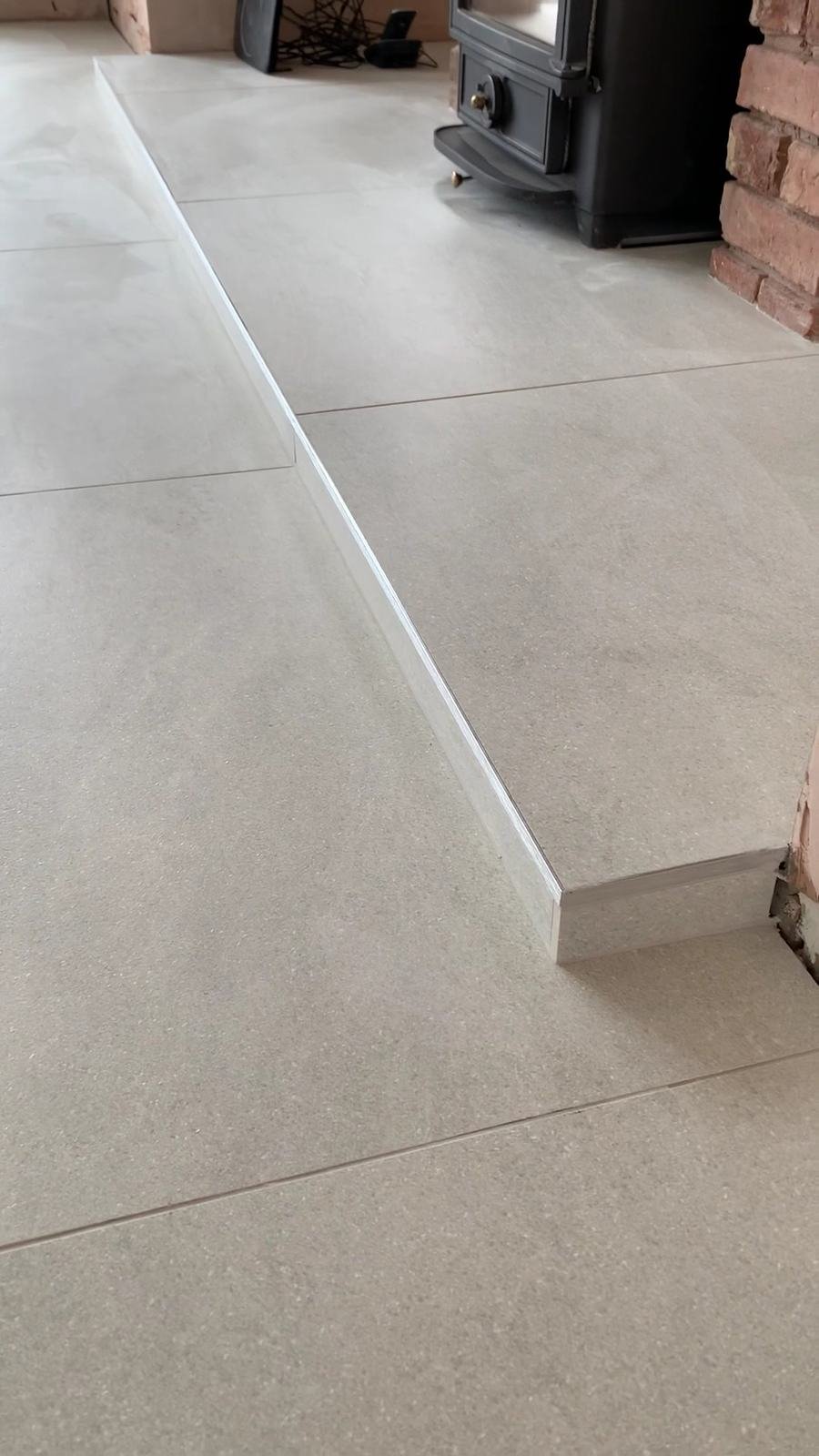 Large grey porcelain tiles running over a step