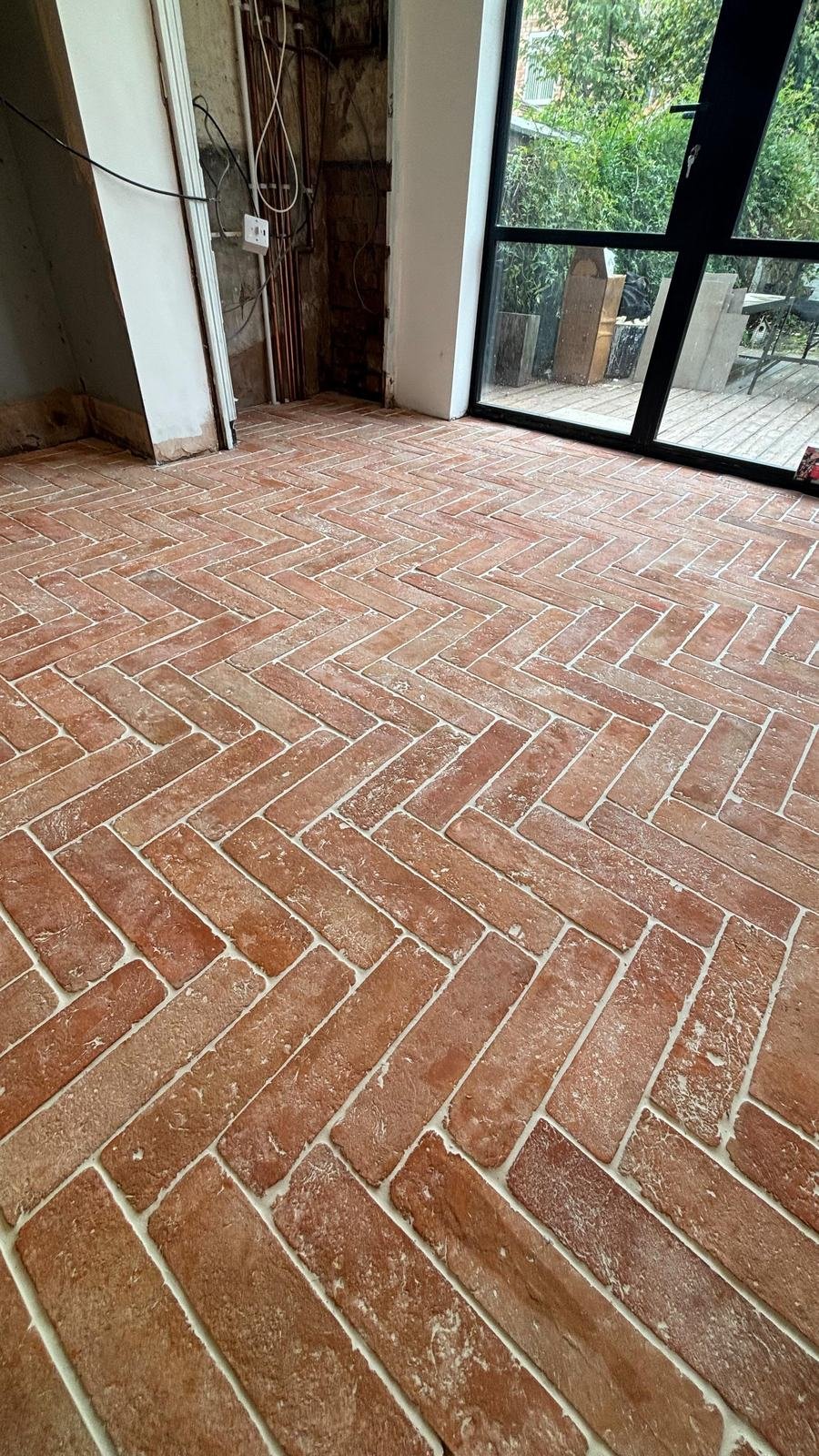 Terracotta brick-style tiles laid in herringbone across a kitchen floor